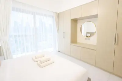 a white bedroom with a mirror and a white bed at Burj Khalifa View 2BR Luxury Apartment in Dubai in Dubai