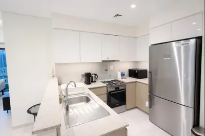 a kitchen with white cabinets and a stainless steel refrigerator at Burj Khalifa View 2BR Luxury Apartment in Dubai in Dubai