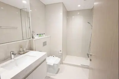 a white bathroom with a sink and a shower at Burj Khalifa View 2BR Luxury Apartment in Dubai in Dubai