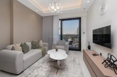a living room with a couch and a tv and a table at Modern 1BR Haven Near the Park, Offering Effortless Connectivity to Key Roads, Cloud A, Jumeirah Village Triangle by Deluxe Holiday Homes in Dubai