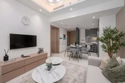 a living room with a couch and a tv on a wall at Modern 1BR Haven Near the Park, Offering Effortless Connectivity to Key Roads, Cloud A, Jumeirah Village Triangle by Deluxe Holiday Homes in Dubai
