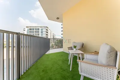 a balcony with green grass and a table and chairs at Walking Distance to Miracle Garden and Butterfly Garden, 20 Minutes Drive to Dubai Marina and Palm Jumeirah - Divine Living, Arjan, by Deluxe Holiday Homes in Dubai