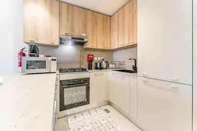 a kitchen with white appliances and wooden cabinets at Walking Distance to Miracle Garden and Butterfly Garden, 20 Minutes Drive to Dubai Marina and Palm Jumeirah - Divine Living, Arjan, by Deluxe Holiday Homes in Dubai