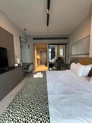 a bedroom with a large white bed and a kitchen at Furnished Studio 2 min Walk to Burji Khalifa in Dubai