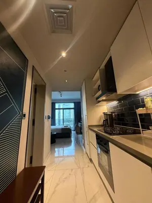 a kitchen with a counter and a living room at Furnished Studio 2 min Walk to Burji Khalifa in Dubai