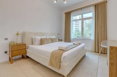 a bedroom with a large white bed and a window at Al Sarrood, Palm Jumeirah - 1 Bedroom Apartment - Allsopp & Allsopp in Dubai