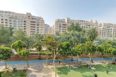 a park in a city with tall buildings at Al Sarrood, Palm Jumeirah - 1 Bedroom Apartment - Allsopp & Allsopp in Dubai