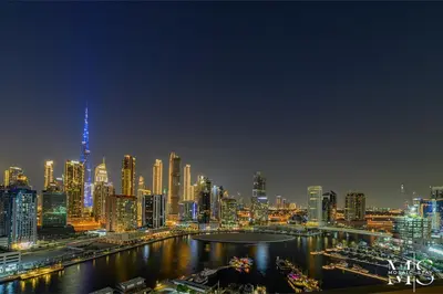 a night view of a city with a river and buildings at Luxury High Floor 1BHK Burj and Canal Views in Dubai
