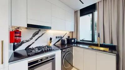 a kitchen with white cabinets and a washer and dryer at Vacationer l 1 Bedroom in Business Bay l Direct Pool Access in Dubai