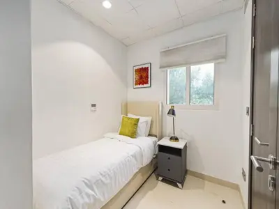 a white bedroom with a bed and a window at Redwood Townhouse Jumeirah Golf Estates in Dubai