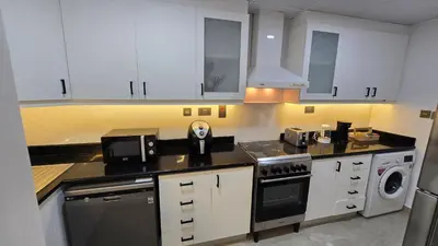a kitchen with white cabinets and a black appliance at Beach, Palm Jumeirah & Marina view in Dubai