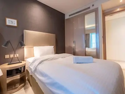 a bedroom with a large white bed and a television at Paramount Tower - Stylish 2BR Apartment with Balcony & Pool - Near Dubai Mall in Dubai