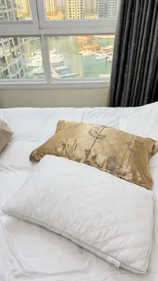 a pillow sitting on top of a bed with a window at Luxury 1BR Apt with water canal & Marina View in Dubai