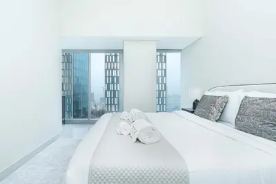 a white bedroom with a large white bed with two rolled towels at PVH - Refined 1BR in Marina - Cayan Tower in Dubai