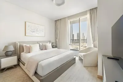 a white bedroom with a large bed and a window at Premium 2BR Burj Khalifa View at Vida Dubai Mall in Dubai