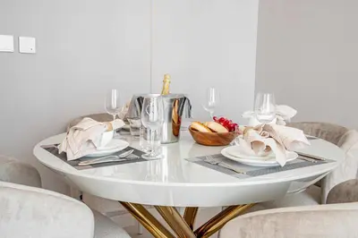 a white dining room table with chairs and a white table with glasses at Frank Porter - Vida Residences Dubai Mall in Dubai