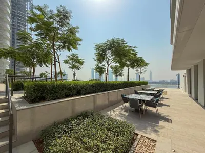 a row of tables and chairs on a balcony with trees at Frank Porter - Palace Beach Residence in Dubai
