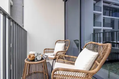 three wicker chairs and a table on a balcony at Frank Porter - Island Park 2 in Dubai