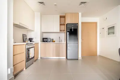 a kitchen with wooden cabinets and a refrigerator at Frank Porter - Island Park 2 in Dubai