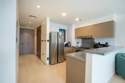 a kitchen with a stainless steel refrigerator and wooden cabinets at Santorini Damac Lagoons Luxury 3BR Villa Mediterrean Bliss in Dubai