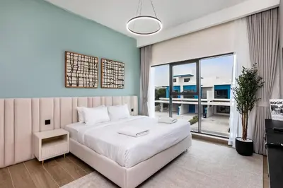 a bedroom with a white bed and a large window at Santorini Damac Lagoons Luxury 3BR Villa Mediterrean Bliss in Dubai