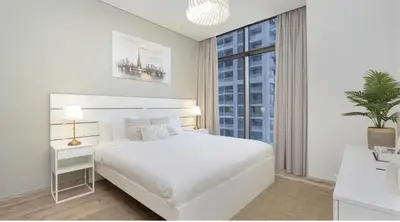 a white bedroom with a white bed and a window at Burj Khalifa and Canal view 2 BDR Apartment in Dubai