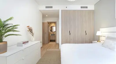 a white bedroom with a white bed and a plant at Burj Khalifa and Canal view 2 BDR Apartment in Dubai