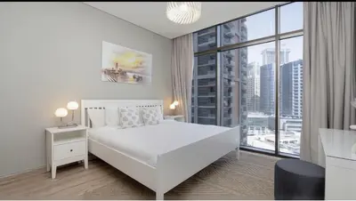 a white bedroom with a white bed and a large window at Burj Khalifa and Canal view 2 BDR Apartment in Dubai