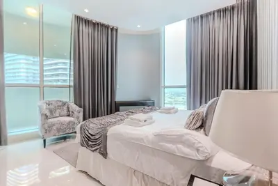 a bedroom with a bed and a chair and windows at TRPS - Uppercrest, Downtown - Burj Khalifa View, Furnished, Near Dubai Mall in Dubai