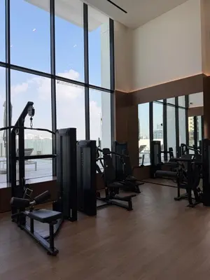 a gym with a bunch of tread machines and windows at High floor luxury apartment JVC in Dubai