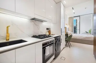 a white kitchen with a stove and a sink at Restay Homes at Binghatti Azure - Great City Escape - Swimming Pool Access in Dubai