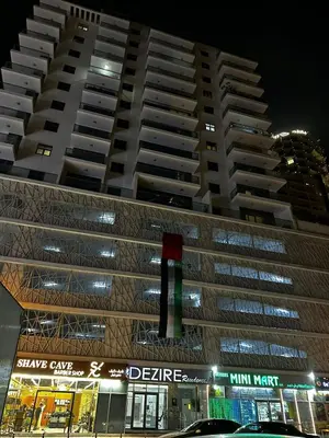 a large apartment building at night with a traffic light at Modern Studio Apartment with Balcony in JVC in Dubai