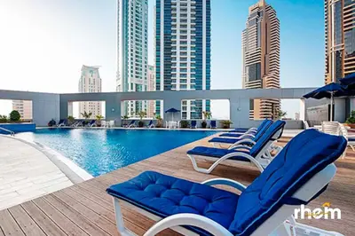 a patio with chairs and a pool on a building at Brand New 2-BR Apartment in Dubai Marina - JBR in Dubai