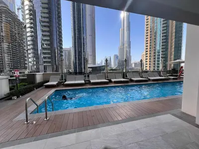 a swimming pool with chairs and a city skyline at 2BR next to Dubai mall with Khalifa Tower view! in Dubai