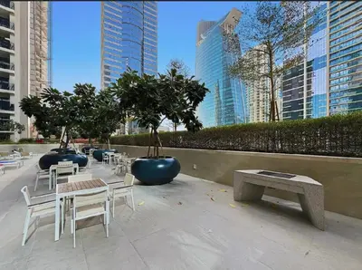 a group of tables and chairs with trees and buildings at Modern Flat close to Burj Khalifa with stunning pool in Dubai