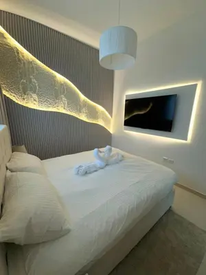 a bedroom with a bed with white sheets and a tv at Modern Flat close to Burj Khalifa with stunning pool in Dubai
