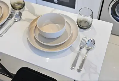 a white bowl and plate on a table with silverware at Modern Flat close to Burj Khalifa with stunning pool in Dubai