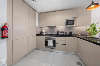 a kitchen with white cabinets and a fire extinguisher at Easy access to Community Parks and Green Spaces,15 minutes drive to Miracle Garden - Rigel, JVC, by Deluxe Holiday Homes in Dubai