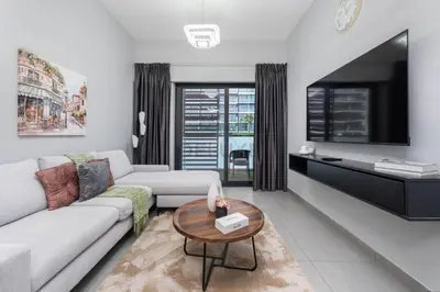 a living room with a couch and a tv at Easy access to Community Parks and Green Spaces,15 minutes drive to Miracle Garden - Rigel, JVC, by Deluxe Holiday Homes in Dubai