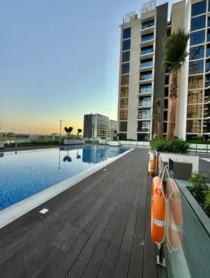 a swimming pool with orange life presleys on a wooden deck at Beautiful Studio Brand New in Dubai