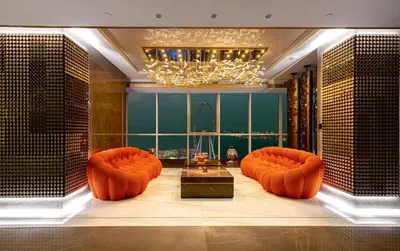 a living room with orange chairs and a chandelier at Sky Palace 3 Bedroom Penthouse on JBR in Dubai