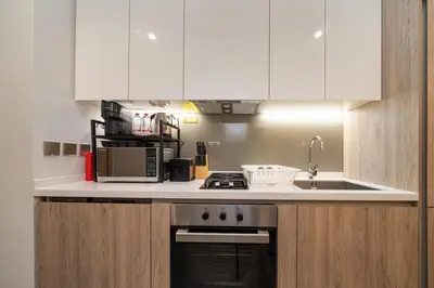 a kitchen with white cabinets and a stove top oven at Stylish Modern Peninsula One Studio, Business Bay in Dubai