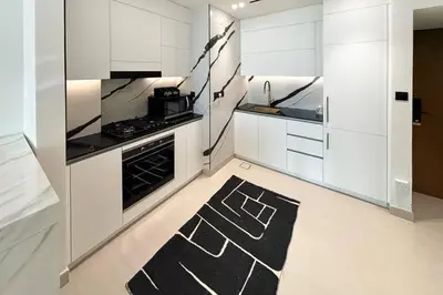 a kitchen with white cabinets and a black and white rug at Modern Place - Trillionaire Residence 608 in Dubai