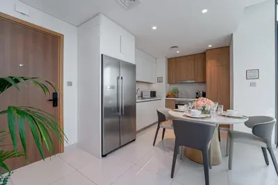a kitchen with a table and a stainless steel refrigerator at 2BR with Atlantis View, Beach Access, and Infinity Pool in Dubai