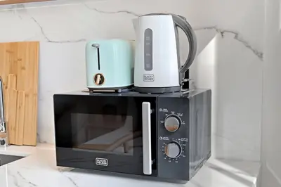 a microwave with a coffee pot on top of it at Aura by Grovy 405 - Parking, Pool&Gym - by Rentujemy in Dubai