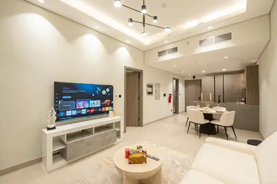 a living room with a television and a dining room at Venetian - Elegant 1BR in JVC & Perfect for Work Leisure in Dubai