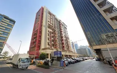 a tall red building with cars parked in a parking lot at Fantubulas Room Partition In Al Barsha 1 in Dubai