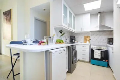 a white kitchen with a sink and a dishwasher at Frank Porter - Bahar 6 in Dubai