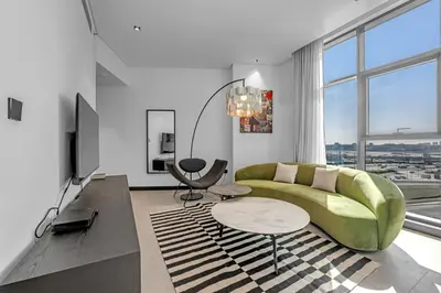 a living room with a green couch and a table at Waves - Chic Business Bay 1BR - Bright and Modern in Dubai