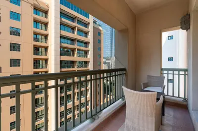 a balcony with two chairs and a view of a building at Walnut Palm 2BR - Palm Jumeirah in Dubai